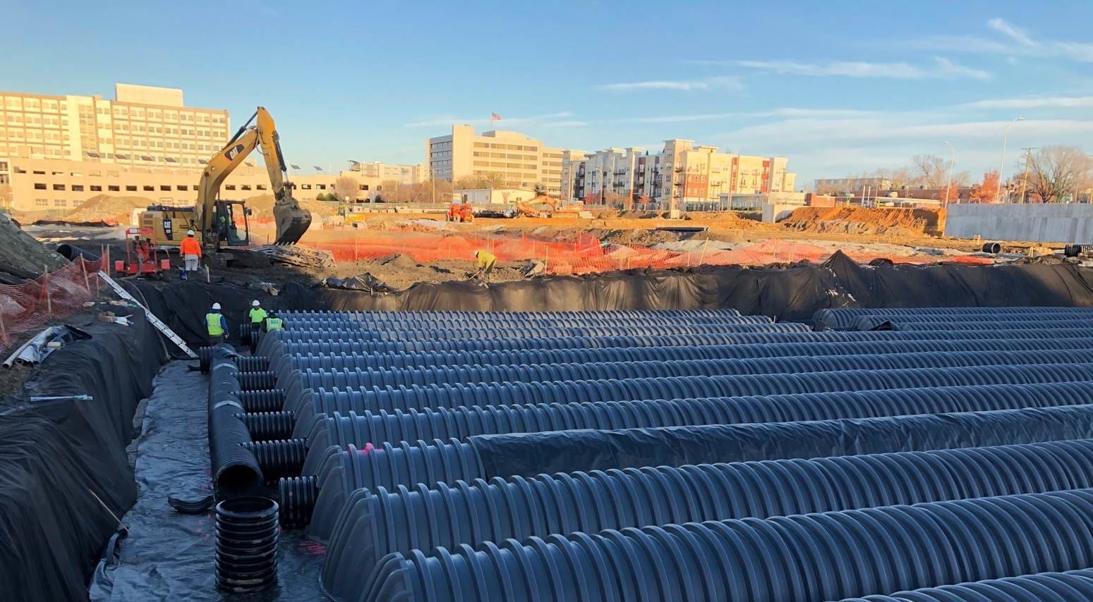 A man standing next to a pile of pipes.