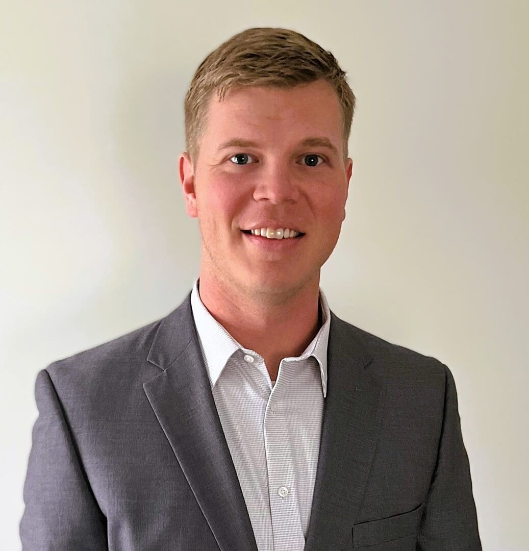 A man in a suit and tie standing next to a wall.